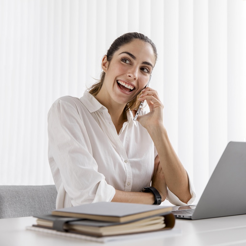vista-frontal-da-sorridente-empresaria-trabalhando-com-smartphone-e-laptop
